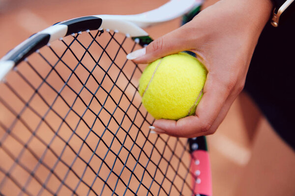 Close-up picture of woman preparing to serve a tennis ball