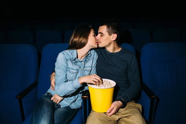 Cinema day. Young beautiful couple kissing while watching romantic movie at cinema. Romantic date in cinema.