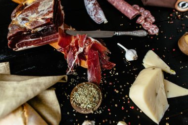 Prosciutto crudo tütsülenmiş sosis, peynir ve baharat siyah ahşap zemin ile
