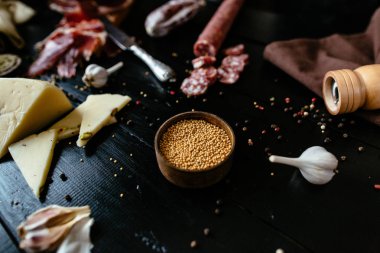 Tütsülenmiş sosis, peynir, sarımsak ve biber mill siyah ahşap zemin üzerine hardal fasulye