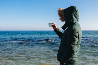 Denizin fotoğrafını çeken adam