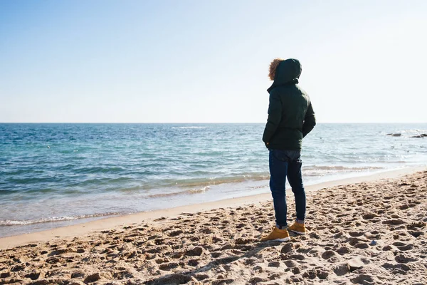 Hombre de pie en la playa y mirando al mar — Foto de Stock