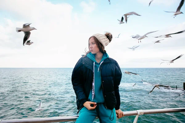 Vacker flicka poserar nära havet med måsar. Stockbild