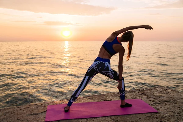 Mujer practicando yoga en la playa al amanecer — Foto de Stock