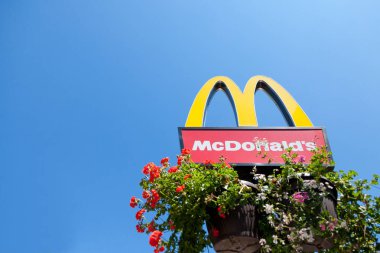 Subotica, Sırbistan - 2 Temmuz 2018: Mc Donald'ın mavi gökyüzü arka plan ve onun altındaki çiçek ile onun ikonik M logolu