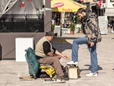 Skopje, Makedonya - 10 Ekim. 2015: Skopje bazar Makedonya sermaye şehir içinde beyaz bir genç adam ayakkabı parlatma shoeshiner