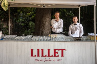 Belgrade, Sırbistan - 14 Temmuz 2018: logosunu ve gözlük olan Lillet yaz çubuk önünde duran iki Garsonlar. Lillet aromatised şaraplar ve kokteyller Fransız bir markasıdır.