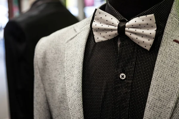 White bowtie with black dots, on display with a black shirt and a white wool suit jacket. Bow ties are a symbol of elegance and style, currently back in the trend