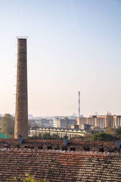 Old brick chimney from an abandoned factory, from the industrial revolution, with a more modern industrial zone can be seen in the background, in Belgrade, Serbia