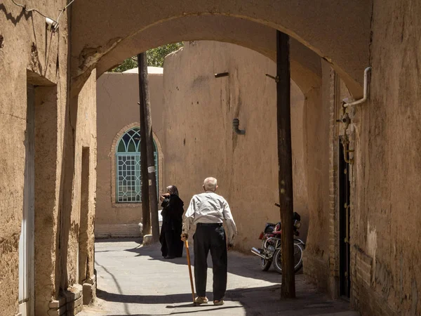 Yazd, Iran - 10 Ağustos 2015: İran büyükler, bir yaşlı adam ve bir yaşlı kadın, eski şehir Yezd, Orta İran'ın ana şehirlerden biri caddelerden birinde yürüyüş