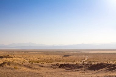 Yukarıda, ön plan ve arka planda bir vadi içinde görünür bir yol ile öğleden sonra: Kashan, Iran yakınındaki Maranjab Çölü'nde da görüleceği Namak Tuz Gölü Panoraması