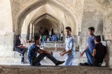 Isfahan, Iran - 20 Ağustos 2016: İran Si o Seh Pol köprü sigara nargile altında toplama ve akıllı telefonlar kullanan gençler. Şehrin ana köprüden 