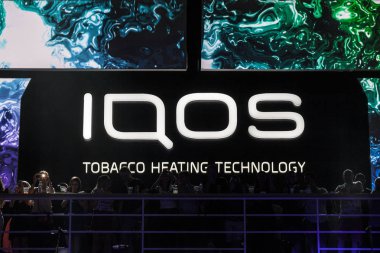 BELGRADE, SERBIA - AUGUST 16, 2018: Iqos logo in front of a bar terrace in Serbia. Iqos, beloning to Philip Morris International, is a tobacco heating cigarette system clipart