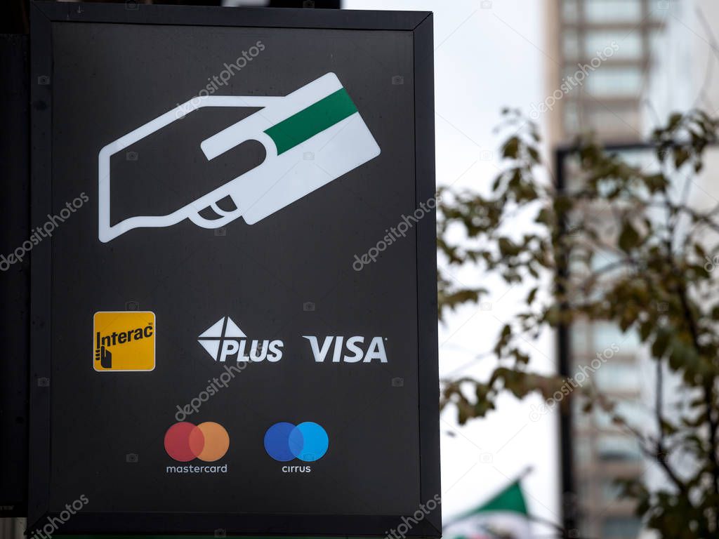 MONTREAL, CANADA - NOVEMBER 7, 2018: Sign on an ATM with the logos indicating the credit and debit pay cards accepted, that include Visa, mastercard, Cirrus, Plus, and the Canadian system Interac
