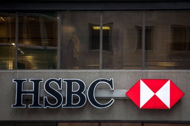 MONTREAL, CANADA - NOVEMBER 8, 2018: Logo of the HSBC Bank, on their main branch in Montreal with cars passing by. HSBC is a british bank spread worldwide clipart