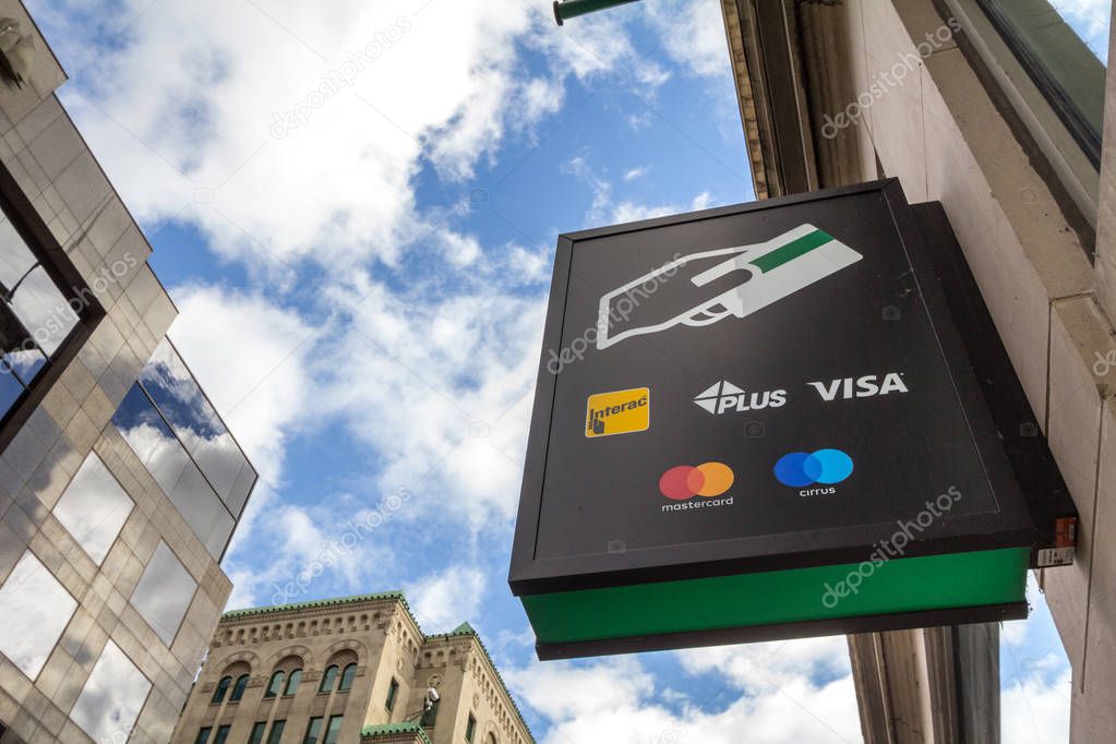 MONTREAL, CANADA - NOVEMBER 7, 2018: Sign on an ATM with the logos indicating the credit and debit pay cards accepted, that include Visa, mastercard, Cirrus, Plus, and the Canadian system Interac