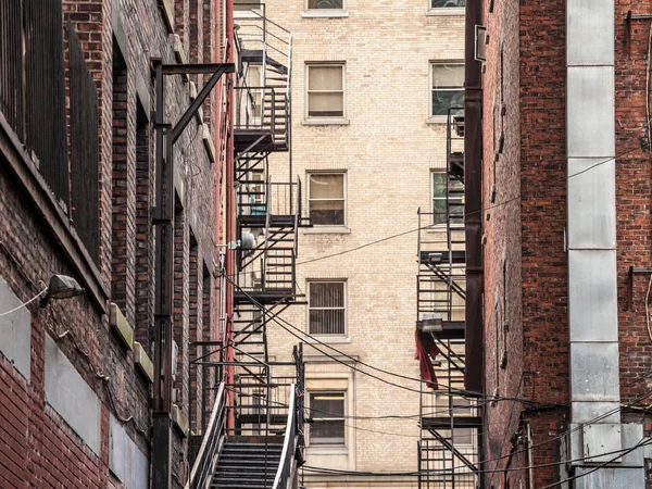Fire escape stairs and ladder, in metal, on a typical North American old brick building from the Old Montreal, Quebec, Canada. These stairs, made for emergency, are symbolic of the American architecture