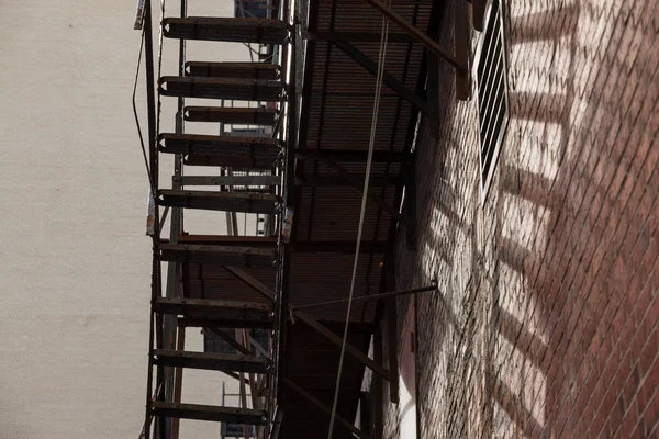 Fire escape stairs and ladder, in metal, on a typical North American old brick building from Montreal, Quebec, Canada. These stairs, made for emergency, are symbolic of the architecture