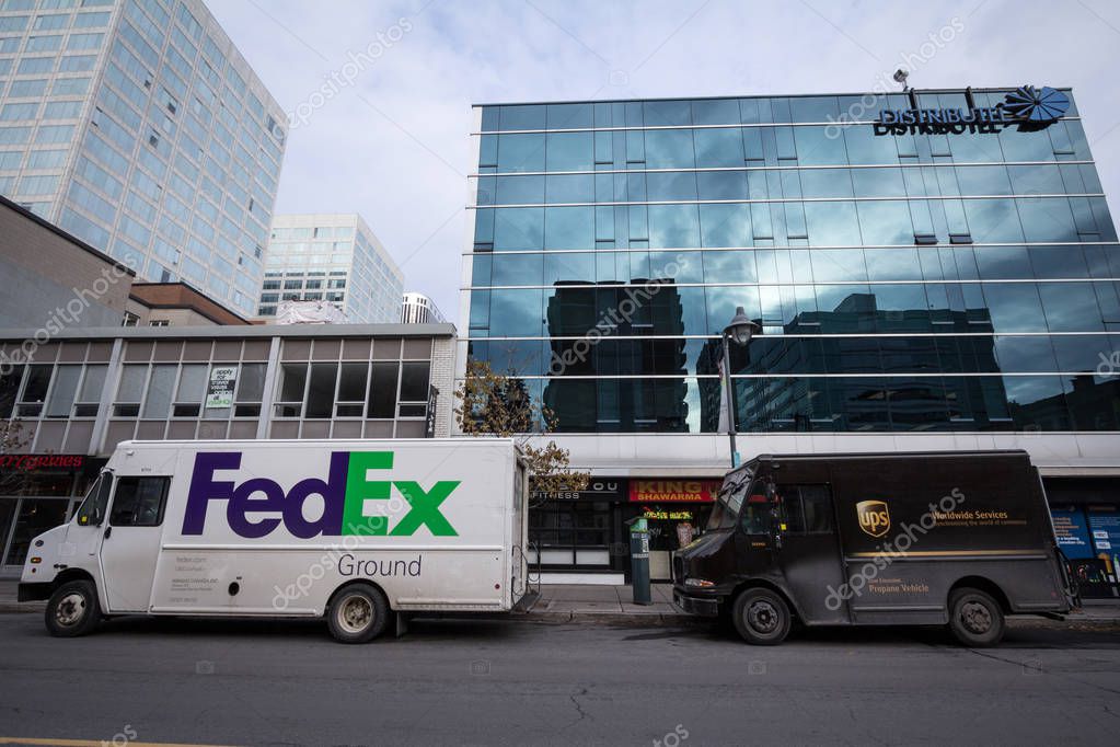 OTTAWA CANADA - NOVEMBER 12, 2018: Fedex & UPS logos on delivery vans next to each other in Ottawa street, Ontario. Fedex & UPS are competing American courier specialized in parcels & letters shipping