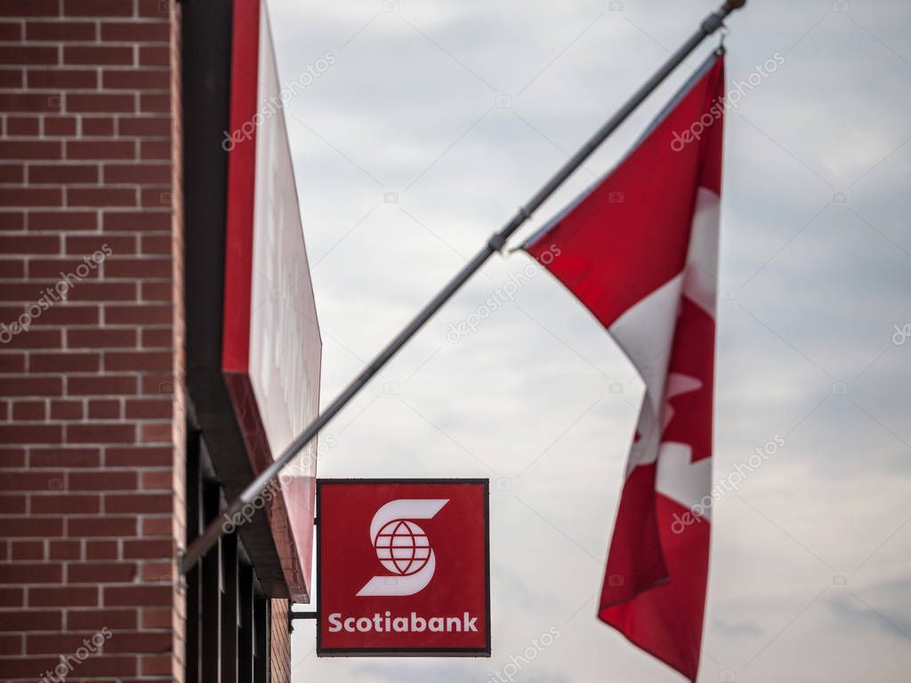 OTTAWA, CANADA - NOVEMBER 12, 2018: Scotiabank logo on a banking center in Ottawa, Ontario with a flag of Canada standing. Called as well Bank of Nova Scotia, it is one of the main banks of America