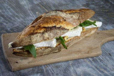 Fransız baget, Brie sanwdich rucola salata rustik ahşap bir masa ekranda bazı dilimleri ile Brie de Meaux peynir yaptı. Bu sandviç, Fransa'da, sandviç au denir brie