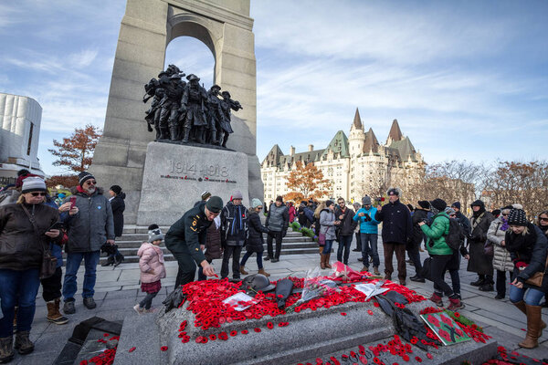 OTTAWA, CANADA - NOVEMBER 11, 2018: soldier putting remembrance poppy in front of a Crowd gathering on National War memorial, on remembrance day to commemorate canadians who died in conflicts