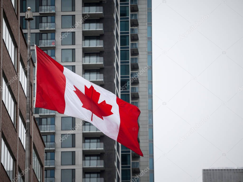 Canadian flag in front of a residential condo apartment building in Montreal, Quebec, Canada. Montreal is main economic and business hubs of Quebec and one of biigest of North America