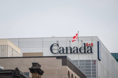 Ottawa, Kanada - 12 Kasım 2018: Kanada hükümetinin resmi logosu Olan Kanada Bayrağı, Kanada bayrağının yanında bir idari binada