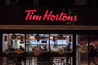 Toronto, Kanada - 14 Kasım 2018: Tim Hortons, Toronto, Ontario'daki restoranlarından birinin önünde gece yayaların geçtiği logo. Tim Hortons bir kafe ve fastfood Kanada markasıdır