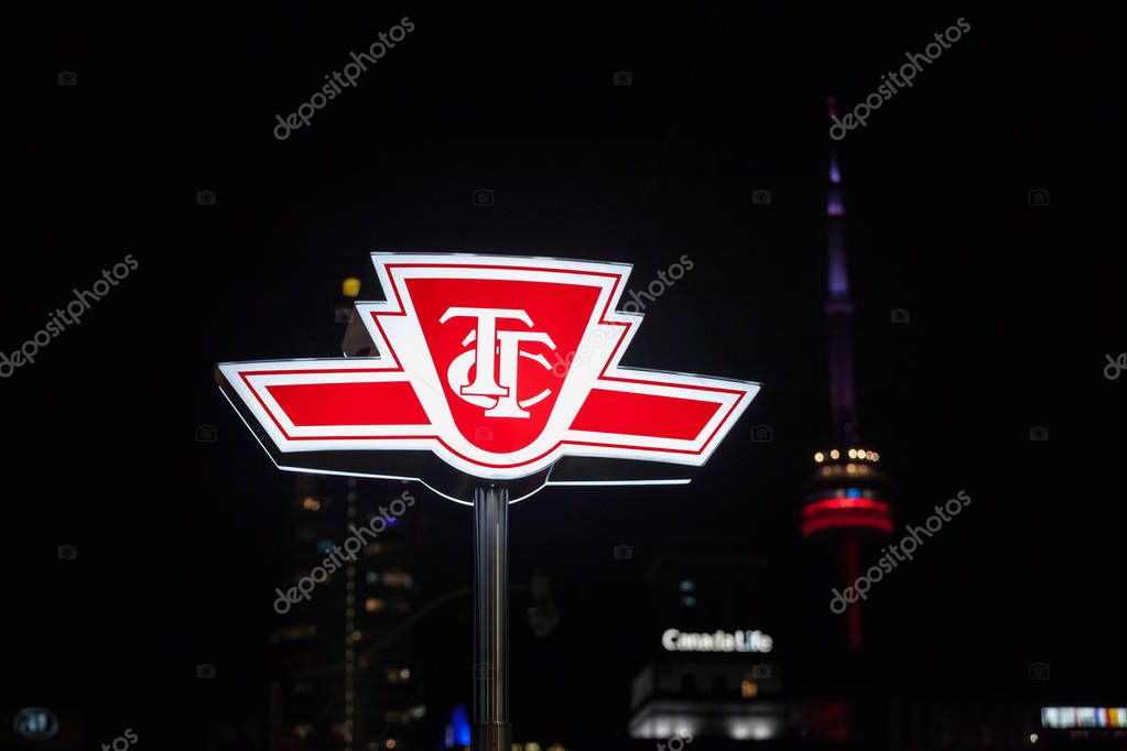 TORONTO, CANADA - NOVEMBER 43, 2018: TTC logo on entrance of subway station in Downtown with CN tower in background. Toronto Transit Commission is the operator of public transport in the city