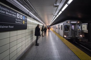 TORONTO, CANADA - NOVEMBER 14, 2018: People waiting for a subway in Spadina station platform, while a metro train operated by TTC, Toronto Transit Commission, is coming, with a speed blurr clipart