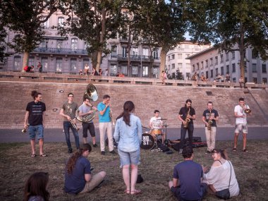 Lyon, Fransa - 18 Temmuz 2019: Akşam ları Rhone nehri kıyısında (quais) oturan insanların önünde pratik yapan müzisyenler grubu, apero geleneği için toplanıyor