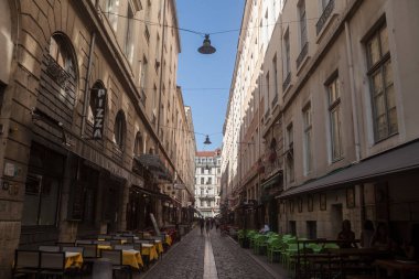 LYON, FRANCE - JULY 19, 2019: Typical narrow street of the Vieux Lyon (old Lyon) on the Presqu'ile district with tourists passing by near restaurants  during a sunny summer afternoon clipart
