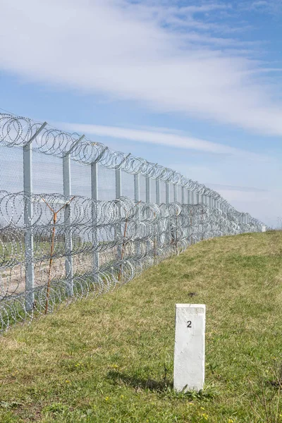 Border fence between Rastina (Serbia) & Bacsszentgyorgy (Hungary) with a boundary marker. This border wall was built in 2015 to stop the incoming refugees & migrants during the refugees crisis, on Balkans Route