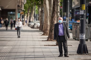 BELGRAD, SERBIA - 27 Nisan 2020: Coronavirus covid 19 sağlık krizi sırasında Belgrad caddesinde yürüyen, solunum maskesi takan yaşlı adam