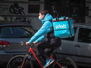 BELGRAD, SERBIA - 6 Mayıs 2020: Belgrad 'daki Coronavirus Covid 19 krizi sırasında yüz maskesi koruyucu solunum cihazı takan Wolt kuryesi. Wolt bir yiyecek teslimatı uygulaması.