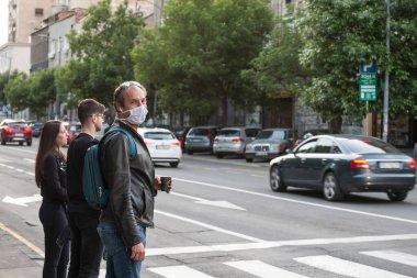 BELGRAD, SERBIA - 8 Mayıs 2020: Coronavirus Covid 19 krizinde elinde maske takan orta yaşlı bir adam sokakta yürüyor