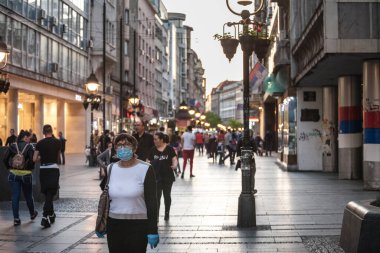 BELGRAD, SERBIA - 8 Mayıs 2020: Coronavirus covid 19 sağlık krizi sırasında Belgrad 'ın kalabalık bir caddesinde yürüyen, solunum maskesi takan yaşlı kadın