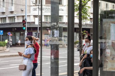 BELGRAD, SERBIA - 9 Mayıs 2020: Coronavirus covid 19 sağlık krizi sırasında Belgrad 'ın otobüs durağında araç bekleyen solunum maskesi takan genç kızlar