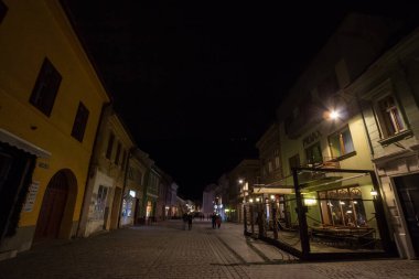 BRASOV, ROMANIA - 13 Şubat 2020: Ortaçağ tarihi merkezi Brasov 'da Strada Michael Weiss Caddesi' nde geceleyin yayalar geçerken. Brasov bir transilvanya tarihi şehridir.