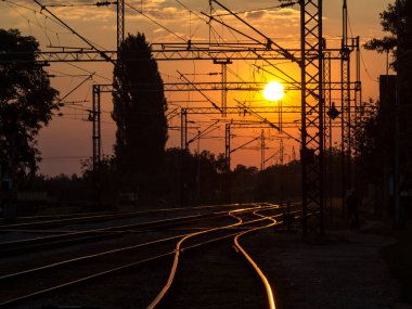 Sırbistan 'ın Sremska Mitrovica kentinde gün batımında demiryolu rayları ve tepe hatları, Balkanlar' da elektrik yüklü bir demiryolu hattının tren istasyonunda