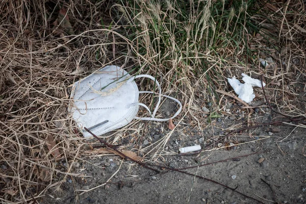 Used face mask, disposable, thrown out on the ground in the environment as garbage during the corovavirus covid 19 crisis. Throwing used face protection in the nature is an environmental issue