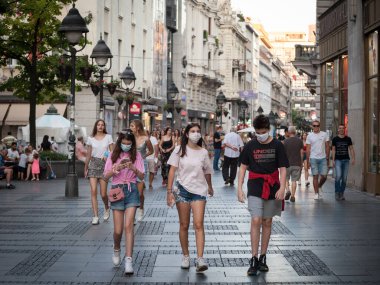 BELGRAD, SERBIA - 29 Temmuz 2020: Genç insanlar, genç adam ve iki genç kız, arkadaşlar, Coronavirus Covid 19 krizinde yüz maskesi koruyucu ekipman takarak yürüyorlar