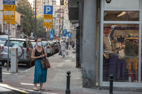 BELGRAD, SERBIA - 13 Ağustos 2020: Coronavirus Covid 19 krizinde maske takan yaşlı kadın Belgrad bulvarında karşıdan karşıya geçmek için bekliyor