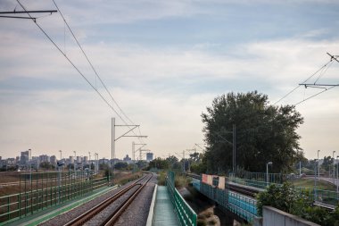 Sırbistan 'ın Belgrad kentindeki banliyö demiryolu ağının elektrikli banliyö hattındaki modern bir tren istasyonunda platform ve köprü. Şehir manzarası arka planda görülebilir