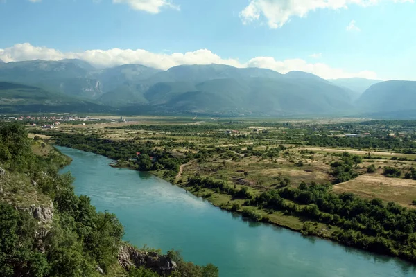 Bosna-Hersek 'in Mostar kenti yakınlarındaki bir vadide yer alan Neretva Nehri' nin arka planında dağlar ve birkaç bulut da suya yansıyor. Neretva Balkanlar 'ın büyük bir nehri