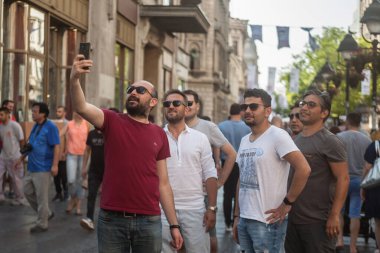 BELGRAD, SERBIA - 27 Temmuz 2019: Bir grup mutlu turist, genç erkek, bekar, mutlu, Belgrad şehir merkezindeki Kneza Mihailova yaya yolunun önünde akıllı bir telefonla selfie çekiyor