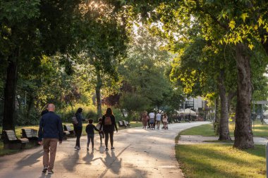 BELGRAD, SERBIA - 19 Temmuz 2020: iki grup, aileleri, babaları, anneleri ve küçük çocukları ile birlikte, yazın Belgrad 'ın en son ilçesi olan Novi' de bir parkta yürüyorlar.