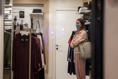 BELGRAD, SERBIA - 22 Eylül 2020: Coronavirus covid 19 sağlık krizi sırasında Belgrad 'da solunum maskesi takan bir perakende giyim mağazasında bekleyen müşteri