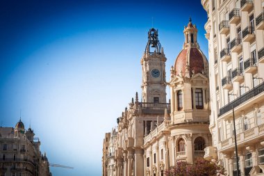Valencia Belediye Binası saat kulesi ve sabah ışığı ile döşenmiş kubbe pırıltısı Plaza del Ayuntamiento 'nun üzerinde açık mavi bir gökyüzüne karşı, İspanya' da Casa Constorial veya palau regarstorial de valencia olarak da bilinir..